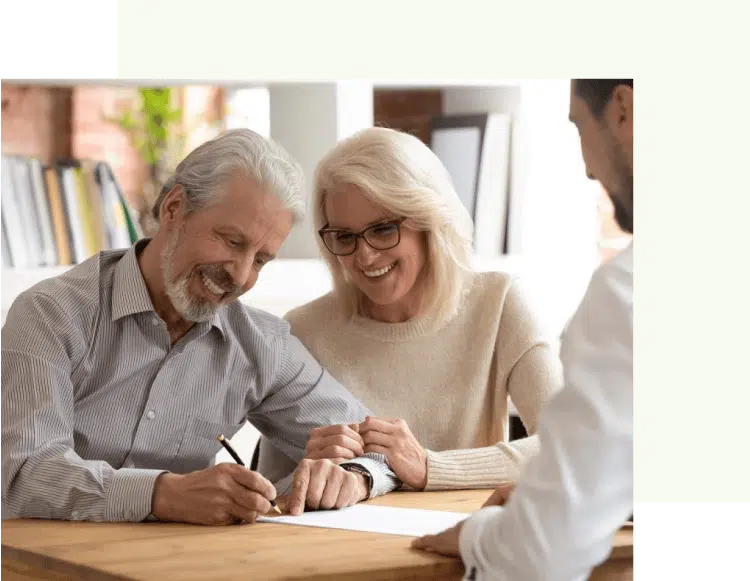 Elderly couple signing documents with a professional advisor at a wooden table, showcasing a collaborative and positive atmosphere in financial planning or legal matters.