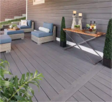 Modern outdoor patio featuring stylish seating, decorative plants, and a wooden table with drinks, set against a contemporary gray wall. Ideal for outdoor entertaining and relaxation.